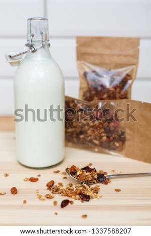 Granola in paper packs without signs with bottle of milk on wooden table