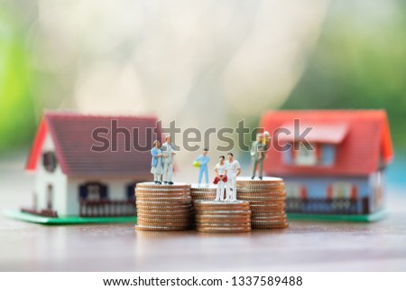 Miniature people: family standing on coins stacks with  house model on the top stack.  concepts. Concept for property ladder, mortgage,real estate investment, money, love and Valentine's day.