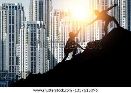 Help, support and friendship in urban life concept. Silhouette people help each other to climb up the mountain in big city.