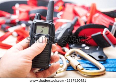radio in the hands of a man, the background blurred climbing equipment