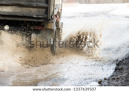 dirty wave of spray from under the wheels of a truck. Water on the road. Spray from under the wheels of cars.