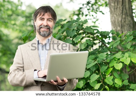 Portrait of happy middle-aged businessman holding notebook and smiling, outdoors