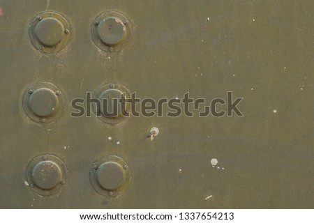 Interesting military retro background. Element of old military equipment close-up. Khaki background - surface khaki color with six protruding elements on the left side and space for text from the righ