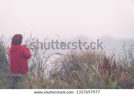 Woman photographer photographs the fog on the lake