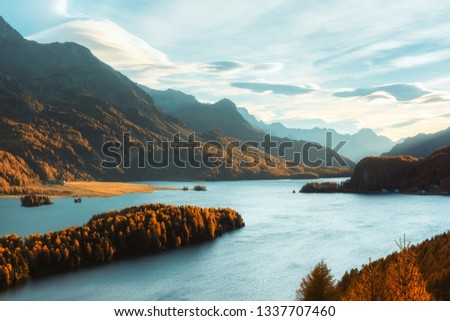 Epic view on autumn lake Sils (Silsersee) in Swiss Alps. Autumn forest with yellow larch on background. Landscape photography