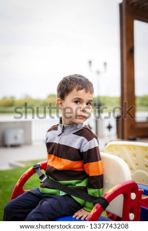 Sweet boy, riding in a train on a merry-go-round, carousel attraction in Europe, active children, summertime