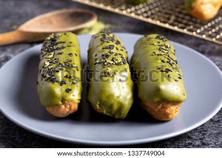 Matcha eclairs topped with black sesame seeds.