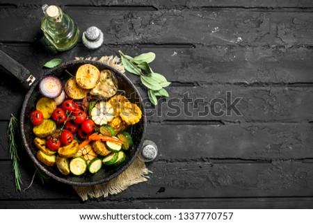 Grilled vegetables on a pan with herbs. On a black rustic background.