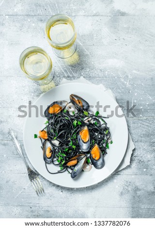 Mediterranean pasta. Spaghetti with cuttlefish ink, clams and white wine. On a rustic background.