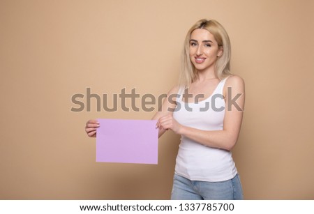 young smiling woman holding a blank sheet of paper for advertising 
