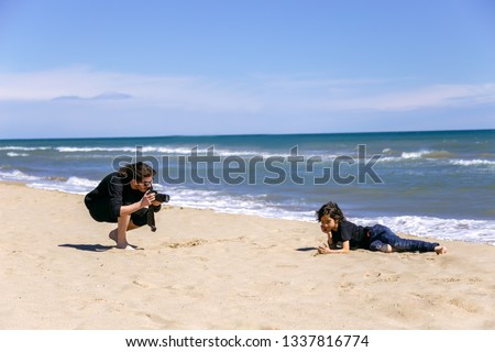 Man taking photo of teenage boy on sandy beach