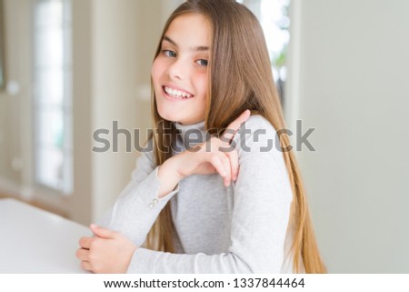 Beautiful young girl kid wearing turtleneck sweater cheerful with a smile of face pointing with hand and finger up to the side with happy and natural expression on face