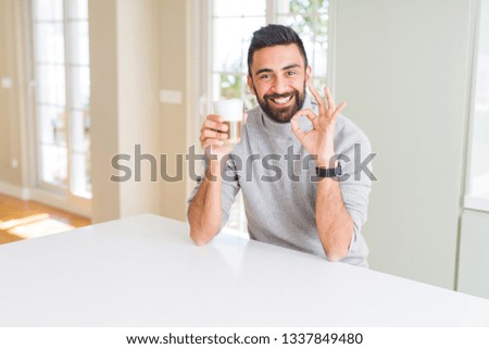 Handsome hispanic man drinking a cup of coffee doing ok sign with fingers, excellent symbol