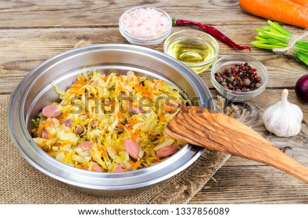 Fried sauerkraut with sausages in metal bowl. Studio Photo