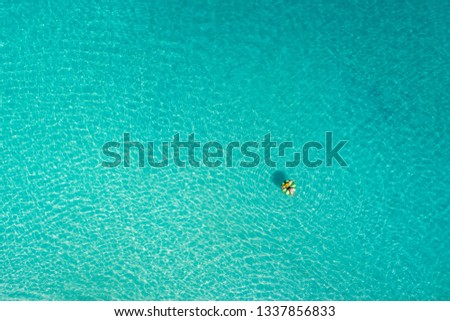 Aerial view of slim woman swimming on the swim ring  donut in the transparent turquoise sea in Seychelles. Summer seascape with girl, beautiful waves, colorful water. Top view 