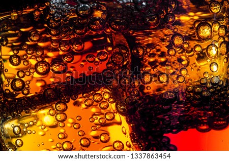 ice cubes in a glass of cola covered with small bubbles