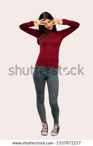 A full-length shot of a Teenager girl with turtleneck counting nine with fingers over isolated background