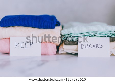 decluttering and tidying up concept: piles of tshirts and clothes being sorted into Keep Discard and Donate categories Royalty-Free Stock Photo #1337893610