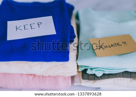 decluttering and tidying up concept: piles of tshirts and clothes being sorted into Keep Discard and Donate categories Royalty-Free Stock Photo #1337893628