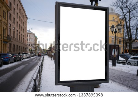 Vertical city billboard with white field MOCKUP. In the city center in the afternoon with snow in the winter outdoor advertising ad