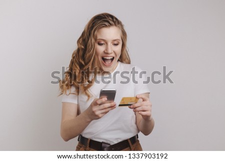 Happy pretty girl making shopping online by her phone and orange credit card.