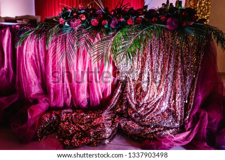 Festive tablen stands decorated with composition of violet, purple, pink flowers and greenery in the banquet hall. Table newlyweds in the banquet area on wedding party.