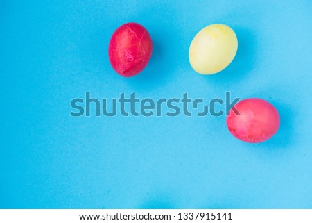 Three colorful Easter eggs lay on a blue background. View from above. Easter theme. Place for text. postcard