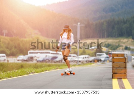 Young girl longboarding downhill on the hillside road