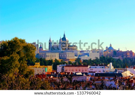 A beautiful colorful panoramic view of the cathedral in Madrid, Spain, west Europe. It is behind residential buldings and close tree branches. On the colorful photo shot you can see three curch domes