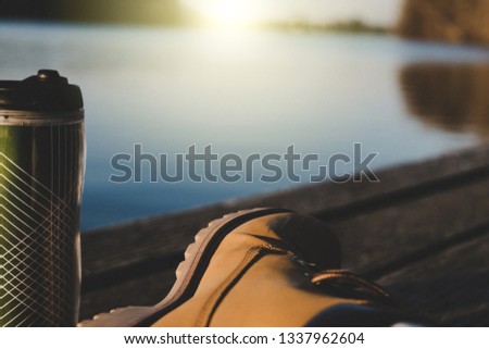 Background of relax chilling man sit waterfront drinking delicious hot coffee, tea under sun in winter spring cold weather. Enjoy and relax on his hobby listen music, read book after work on sunny day