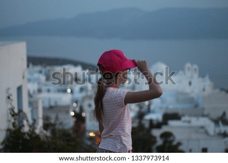 a girl looking over a little town with white houses right after the sunset