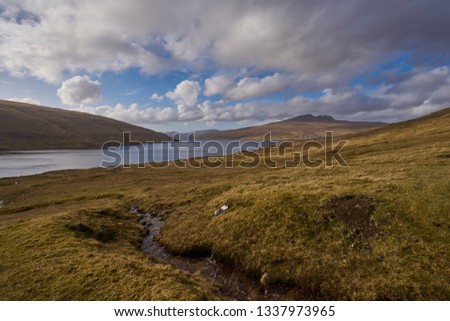 Scenic Picture of wild scandinavian nature without trees with lake Leitisvatn on the island Vagar in Faroe islands in north atlantic during spring sunny day. Faroe islands, part of Kingdom of Denmark 