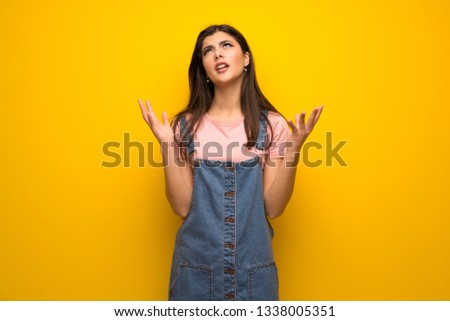 Teenager girl over yellow wall frustrated by a bad situation