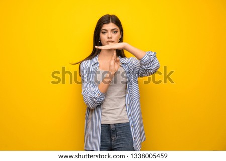 Teenager girl over yellow wall making time out gesture