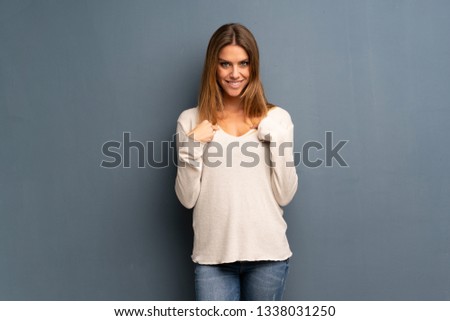 Blonde woman over grey background with surprise facial expression