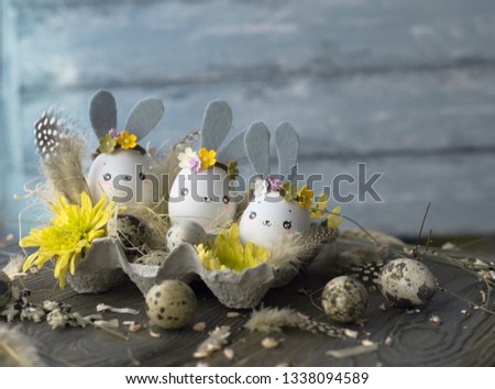 Easter background, homemade eggshells rabbits and yellow chrysanthemum in cardboard boxes over wooden background for beautiful holiday card design