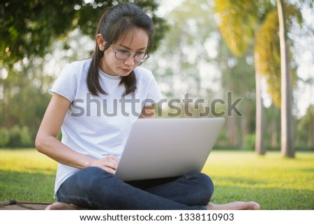 Young Asian Student Using Laptop for search information from internet in the garden at home.