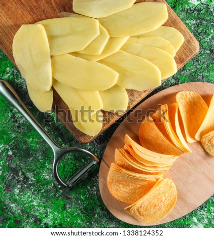 Sliced raw potatoes, ready fried chips on green concrete background. The process of making homemade chips. Step by step. Top view.
