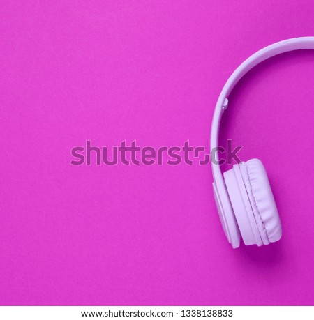 Half of purple headphones on pink background. Top view. Copy space