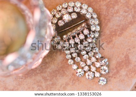 A hair piece with diamonds next to a bottle of women's' perfume. 