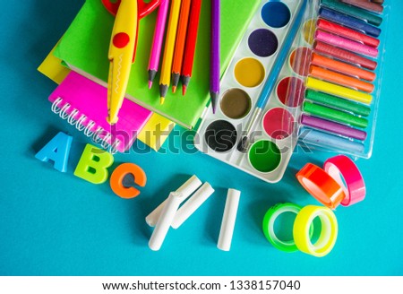 Stationery for study at school lies on blue. Back to school. Books and textbook, apple material for creativity. View from above.Rainbow color