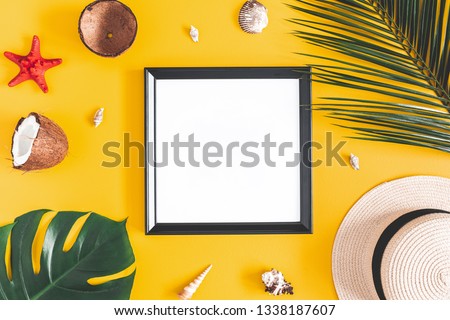 Summer composition. Tropical palm leaves, photo frame, coconut, hat on yellow background. Summer, nature concept. Flat lay, top view, copy space