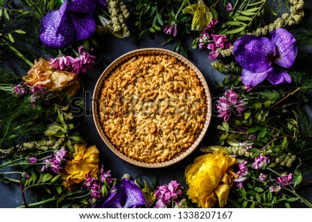 Bouquet of bright flowers and apple pie lying on gray background. Flat lay. Top view