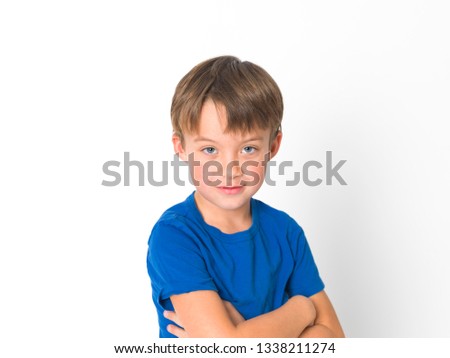 six year old boy in red trousers and blue shirt is posing in front of white background