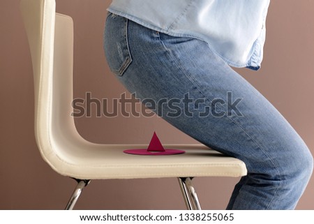 Woman is going to sit on paper pin against color background. April Fool's Day prank