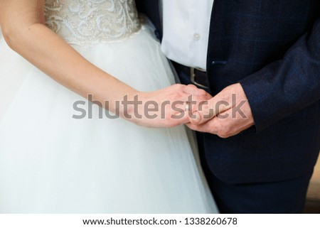 The groom holds the bride's hand in nature