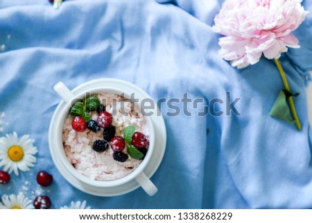 Jars of natural white yogurt with fruit salad with pink dragon fruit, berries and mint on table. Healthy eating. Copy space.blue background with pink and white flowers