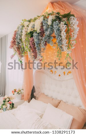 The interior is festive with white wooden vintage arch, beautiful pink chair, flowers, glowing garlands and decorations, photozone