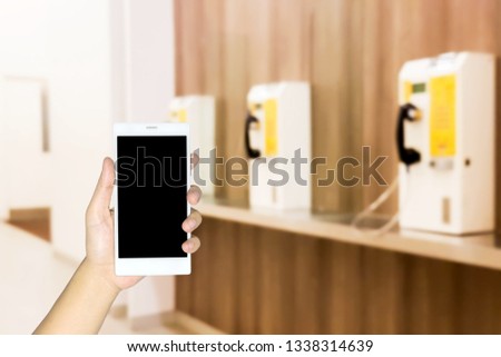 Man use mobile phone, blur image of coin-operated phone inside the mall.