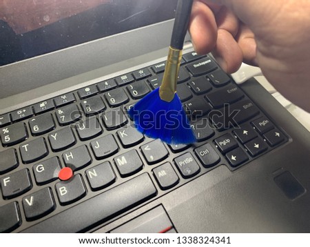 Cleaning keyboard and caring computer. Male hand with a brush to remove dust from the keyboard.Image contain certain grain or noise and soft focus.